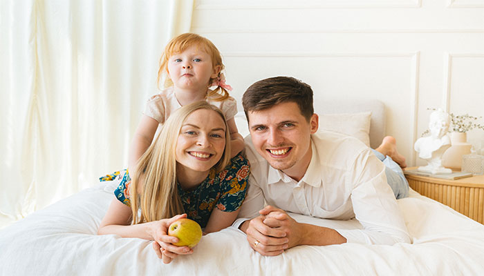 Eine junge Familie liegt auf ihrem Bett in ihrem Eigenheim